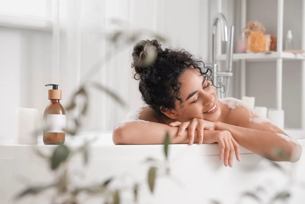 A smiling woman soaking in a bath.