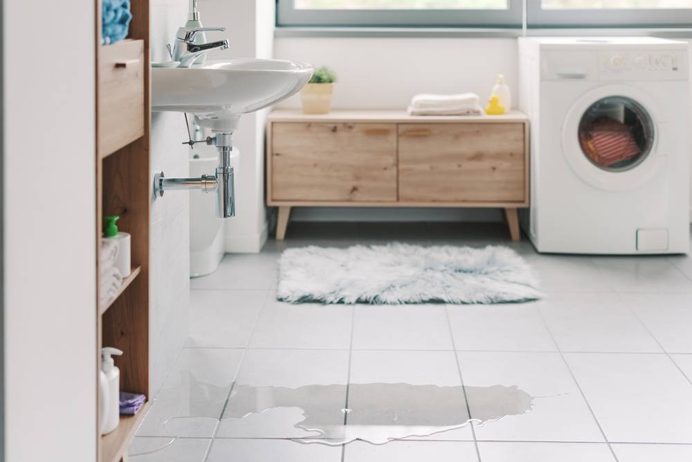 A bathroom with a big wet spot on the tile floor.